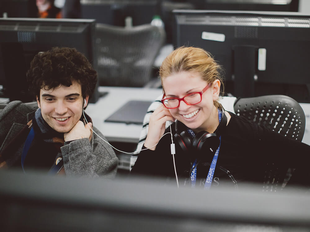 Students in classroom smiling at a computer screen