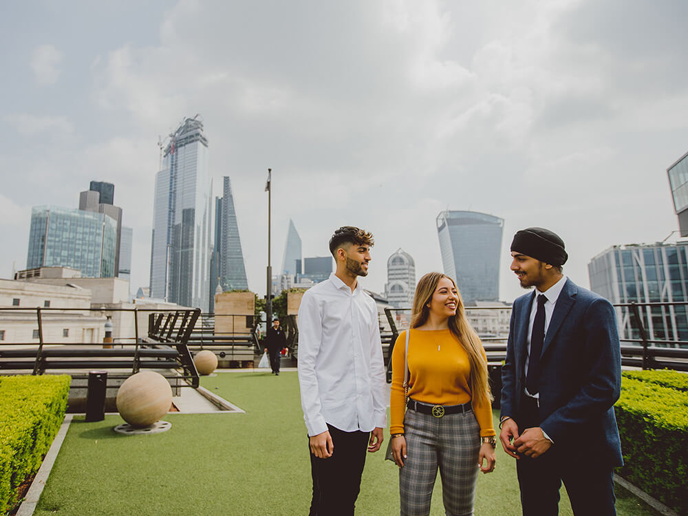 Group of students on a roof garden with the London skyline in the background