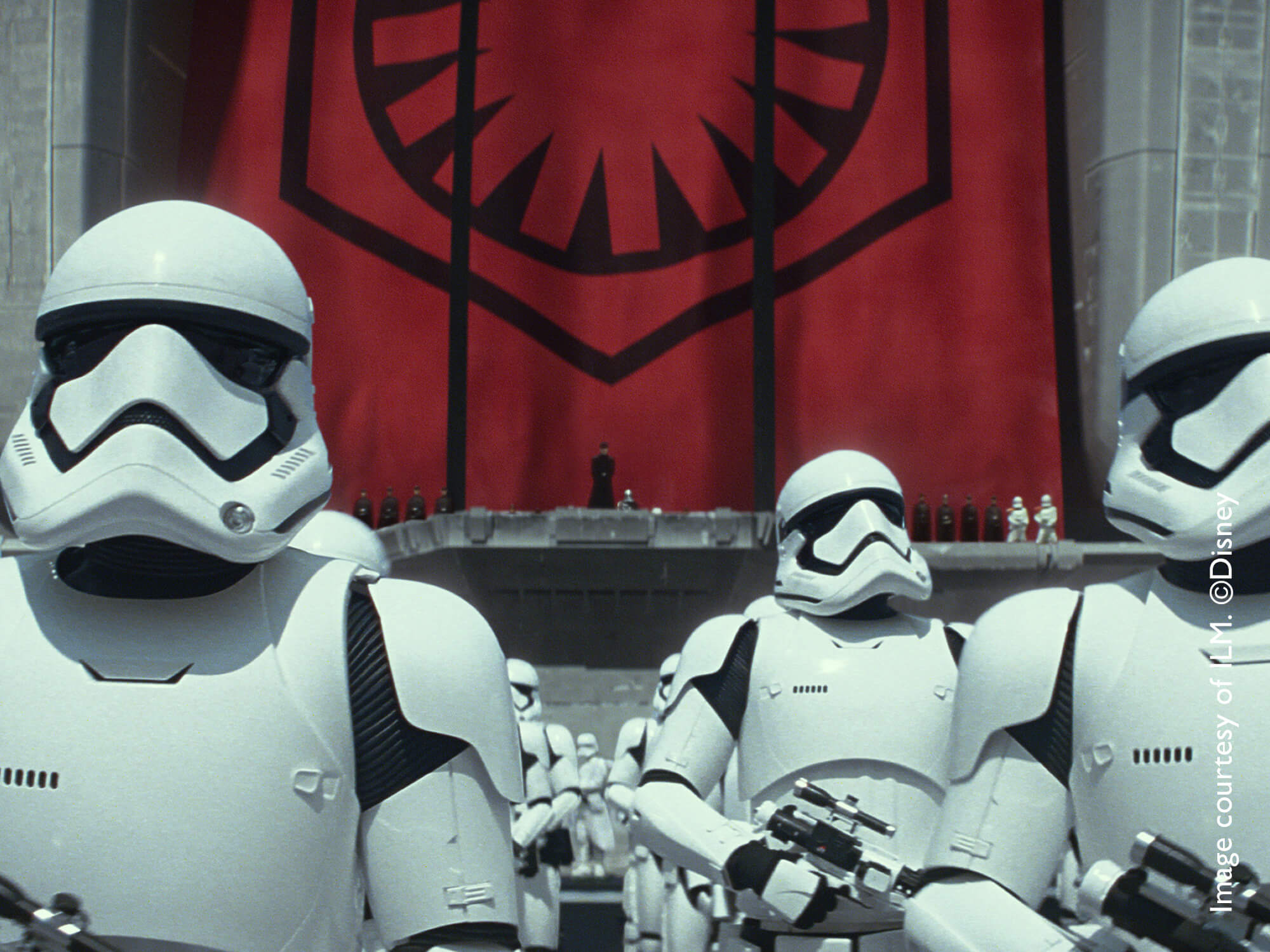 Star Wars stormtroopers standing in formation with red curtain in background